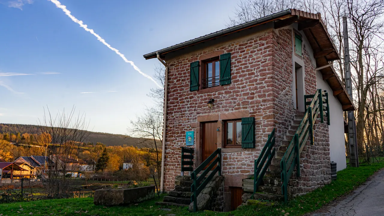 La maison en grès rose et ses volets verts, au-dessus du village